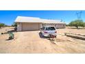 Single story home with a light colored roof and stucco walls, on a large dirt lot with car parked out front at 22222 W Lower Buckeye Rd, Buckeye, AZ 85326