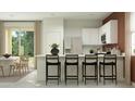 Modern kitchen featuring sleek white cabinets, stainless steel appliances, and a breakfast bar overlooking the dining area at 23361 W Atlanta Ave, Buckeye, AZ 85326