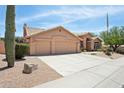 Tan single-story home featuring a three-car garage, desert landscaping and a tile roof at 4401 E Barwick Dr, Cave Creek, AZ 85331
