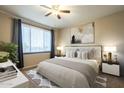 Cozy bedroom featuring a ceiling fan, a plush bed with decorative pillows, and large window at 5345 E Van Buren St # 305, Phoenix, AZ 85008