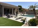 Lush backyard featuring a pristine pool, well-manicured lawn, and relaxing lounge area at 7940 E Quill Ln, Scottsdale, AZ 85255