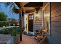 Charming front porch with brick flooring, hanging plants, and seating, offering a welcoming view towards the backyard pool at 8037 E Krail St, Scottsdale, AZ 85250