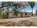 Exterior shot of single-story house with gravel yard and mature landscaping providing shade and curb appeal at 8101 E 4Th Ave, Mesa, AZ 85208