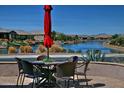 Lakeside patio seating area with a table, chairs, red umbrella, and picturesque water views at 20211 N Winter Escape Ct, Maricopa, AZ 85138