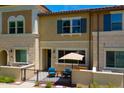Charming two-story townhouse with tan stucco exterior and a cozy front patio with blue chairs and a small table at 2628 S Voyager Dr # 104, Gilbert, AZ 85295