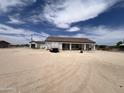An exterior of a one-story white home with a brown roof and a detached garage situated on a large gravel lot at 29935 W Roosevelt St, Buckeye, AZ 85396