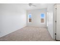 Bright and airy bedroom featuring neutral carpet, two windows providing ample light, and a ceiling fan at 3113 E Danbury Rd # 10, Phoenix, AZ 85032