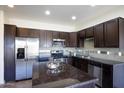Modern kitchen boasts stainless steel appliances, dark wood cabinets, a stylish backsplash, and an island with a granite countertop at 3113 E Danbury Rd # 10, Phoenix, AZ 85032