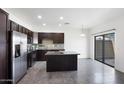 Open concept kitchen with stainless steel appliances, dark cabinets, island, and sliding doors to the backyard, showcasing modern design at 3113 E Danbury Rd # 10, Phoenix, AZ 85032