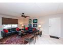 Bright living room features neutral walls, tile floor, black sofas with red pillows, and ceiling fan at 4201 E Camelback Rd # 51, Phoenix, AZ 85018