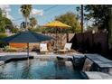 Inviting pool area featuring lounge chairs, umbrellas, waterfall feature, and lush landscaping in the background at 5541 E Cheery Lynn Rd, Phoenix, AZ 85018