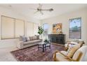 Cozy living room with neutral tones, a ceiling fan, large windows, and stylish furnishings at 6781 W Lone Cactus Dr, Glendale, AZ 85308