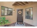 Close-up of the front door with a decorative wreath, security door, and a welcoming mat at 7575 E Indian Bend Rd # 1142, Scottsdale, AZ 85250