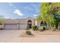 Beautiful home exterior featuring desert landscaping, a tile roof, and a three-car garage at 9678 E Voltaire Dr, Scottsdale, AZ 85260
