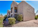 Residential two-story building featuring tan stucco and blooming bushes underneath a bright blue sky at 14910 N Kings Way # 105, Fountain Hills, AZ 85268