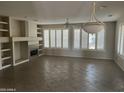 Open living room featuring built-in shelving, a fireplace, tile floors, plantation shutters and a ceiling fan at 15314 W Camino Estrella Dr, Surprise, AZ 85374