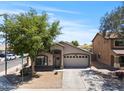 Attractive home with a manicured lawn, mature tree, and convenient two-car garage at 23645 W Parkway Dr, Buckeye, AZ 85326