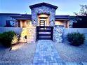 Inviting front entrance with stone accents, a walkway, and modern black gate to a well-lit, single-story home at 4008 La Ultima Piedra --, Carefree, AZ 85377