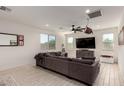 Bright living room featuring light wood-look floors, a large window and a gray sectional couch at 40213 W James Ln, Maricopa, AZ 85138