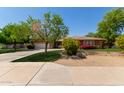Inviting single-story home with lush lawn, mature trees, colorful flowers, and a two-car garage at 4404 W Olney Ave, Laveen, AZ 85339