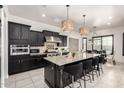 Chef's kitchen with island, stainless appliances, black cabinets, and open to dining area at 5212 S Seton Ct, Gilbert, AZ 85298