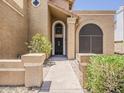 Inviting entryway with elegant archways, lush greenery, and a well-lit pathway creating a warm and welcoming ambiance at 13064 N 100Th Pl, Scottsdale, AZ 85260