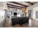 Open living room featuring travertine flooring, stone fireplace, wood beams, and large windows with desert views at 13931 E Via Linda --, Scottsdale, AZ 85259