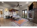 Luxurious primary bedroom with stone fireplace, travertine flooring, sitting area, and outdoor access at 13931 E Via Linda --, Scottsdale, AZ 85259