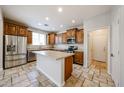 Open kitchen with wood cabinetry, stainless appliances, an island, and travertine floors at 16475 N 183Rd Dr, Surprise, AZ 85388