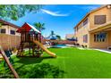 Gathering-friendly backyard featuring a pool, swing set, patio seating, and lush artificial turf, perfect for outdoor fun at 16565 W Garfield St, Goodyear, AZ 85338