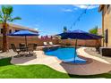 Beautiful backyard pool featuring a rock waterfall, lounge chairs, outdoor seating, and a lush green lawn at 16565 W Garfield St, Goodyear, AZ 85338