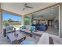Inviting covered patio with comfortable seating, ceiling fan, and access to both the backyard and the home's interior at 18000 W Thistle Landing Dr, Goodyear, AZ 85338