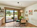 Cozy dining area with glass table, stylish chairs, and sliding glass doors leading to backyard at 19025 N 96Th Ave, Peoria, AZ 85382