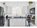 Well-lit kitchen featuring white cabinets, black appliances, and a functional layout at 1941 S Pierpont Dr # 2015, Mesa, AZ 85206