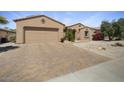 Desert home with brick-paved driveway and neutral toned facade under a sunny blue sky at 19714 N Concord Dr, Surprise, AZ 85374