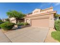 A tan two-story home, with a terra cotta roof, has well manicured shrubs and a two car garage at 22063 N 77Th St, Scottsdale, AZ 85255