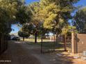 Property entrance with large gate, mature trees, and a partial view of the main house at 25722 S 179Th St, Queen Creek, AZ 85142