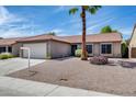 Single-story home with desert landscaping, mature palm tree, and a two-car garage with a concrete driveway under a sunny sky at 2730 E Desert Trumpet Rd, Phoenix, AZ 85048