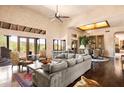 Spacious living room features a large sofa, high ceilings, wood floors, and mountain views through the windows at 41503 N 109Th Pl, Scottsdale, AZ 85262