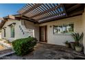 Inviting front entry with shaded pergola, white brick facade, slate patio, and lovely potted plants at 5333 E Sheena Dr, Scottsdale, AZ 85254