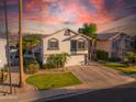 An elevated exterior view of a two-story home with a two-car garage, desert landscaping, and a sunset sky at 7463 E Monte Ave, Mesa, AZ 85209