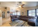 An open-concept living room featuring tile flooring, a ceiling fan, and a large leather sectional sofa at 7463 E Monte Ave, Mesa, AZ 85209