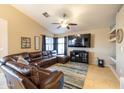 An open-concept living room featuring a ceiling fan, a TV, and a comfortable leather sectional sofa at 7463 E Monte Ave, Mesa, AZ 85209