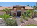 Elegant single-story home featuring a stone accent entryway, double wooden doors, and beautiful desert landscaping at 10450 E Terra Dr, Scottsdale, AZ 85258