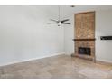 Bright living room featuring a decorative fireplace, neutral walls, travertine floors, and a modern ceiling fan at 10450 E Terra Dr, Scottsdale, AZ 85258