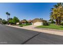 Exterior view of home, featuring desert landscaping, mature trees, and an attached two-car garage at 12711 W Omega Dr, Sun City West, AZ 85375