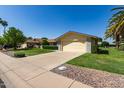 Lovely single-story home with desert landscaping, a well-manicured lawn, and an attached two-car garage at 12711 W Omega Dr, Sun City West, AZ 85375