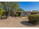 Inviting single-story home with a well-maintained desert landscape, mature trees, and a charming arched entryway at 1541 E Cinnabar Ave, Phoenix, AZ 85020