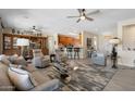 Open-concept living area featuring hardwood floors, multiple ceiling fans, a wet bar, and seamless flow into the kitchen at 15502 W Agua Linda Ln, Surprise, AZ 85374