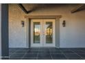 Covered entrance featuring French doors, textured stucco and gray trim at 15612 S Tuthill Rd, Buckeye, AZ 85326